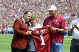 OU AD Joe Castiglione presents a jersey to David Wright's parents. The former Sooner track athlete gave his life serving in Afghanistan.